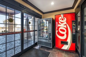 Máquina automática de Coca-Cola e porta automática de segurança em um ambiente comercial.