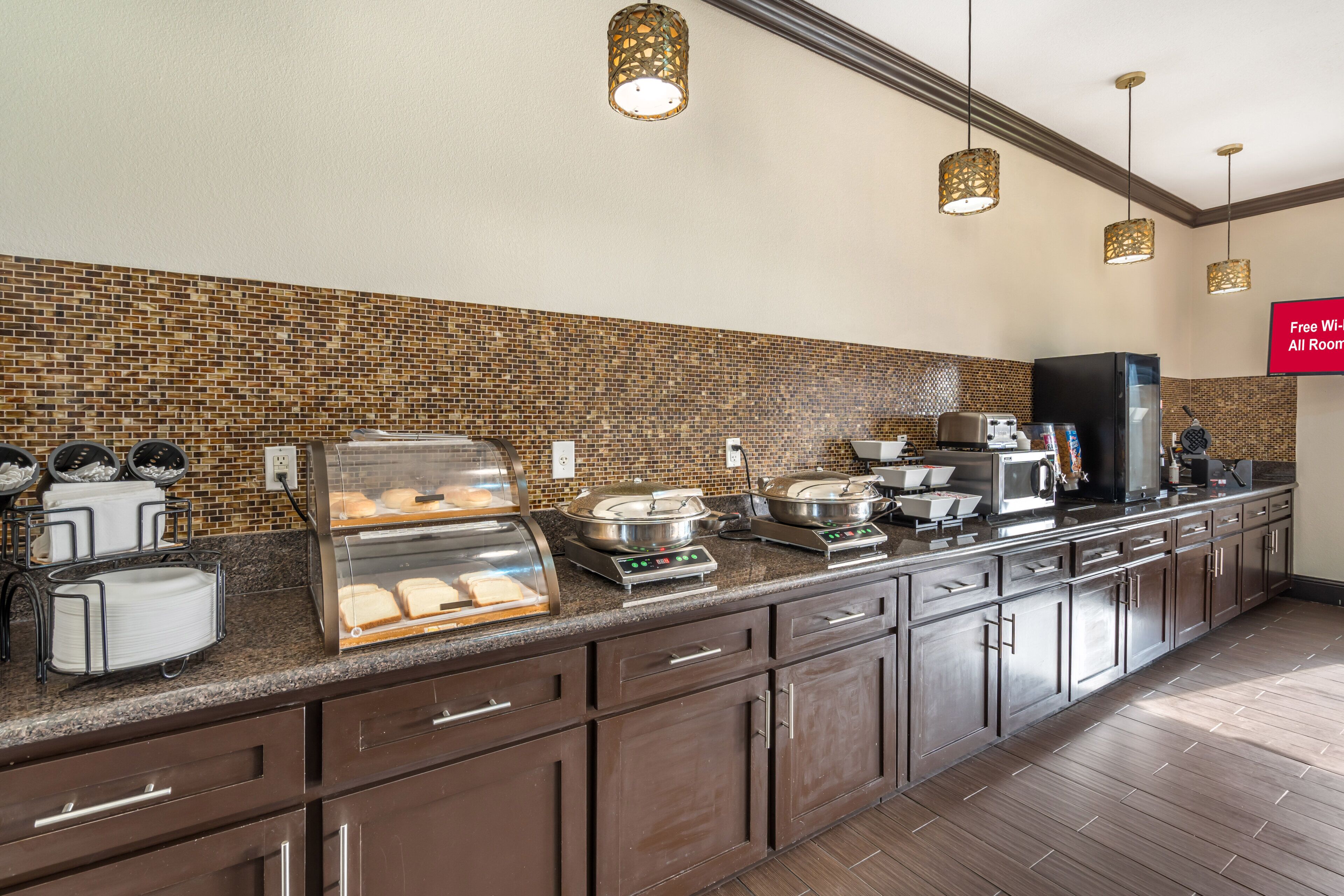 A hotel kitchen with a buffet area, a coffee station, and a sign indicating free Wi-Fi availability.