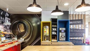 Un área de cocina moderna con una isla central, iluminación colgante y una cafetera.
