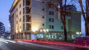 Un hotel de varios pisos con un restaurante en la planta baja y una entrada visible.