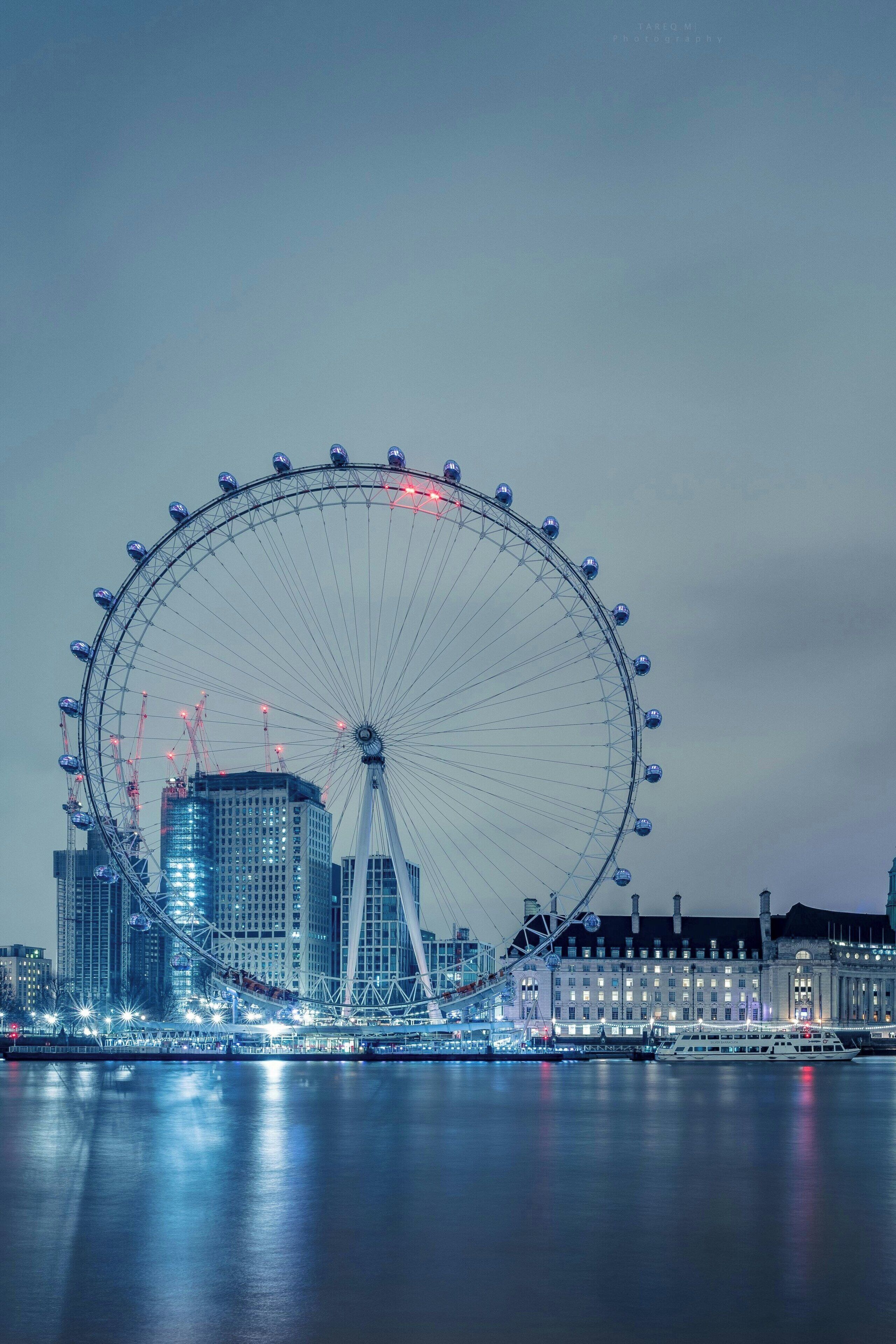 A large Ferris wheel in a cityscape at night.