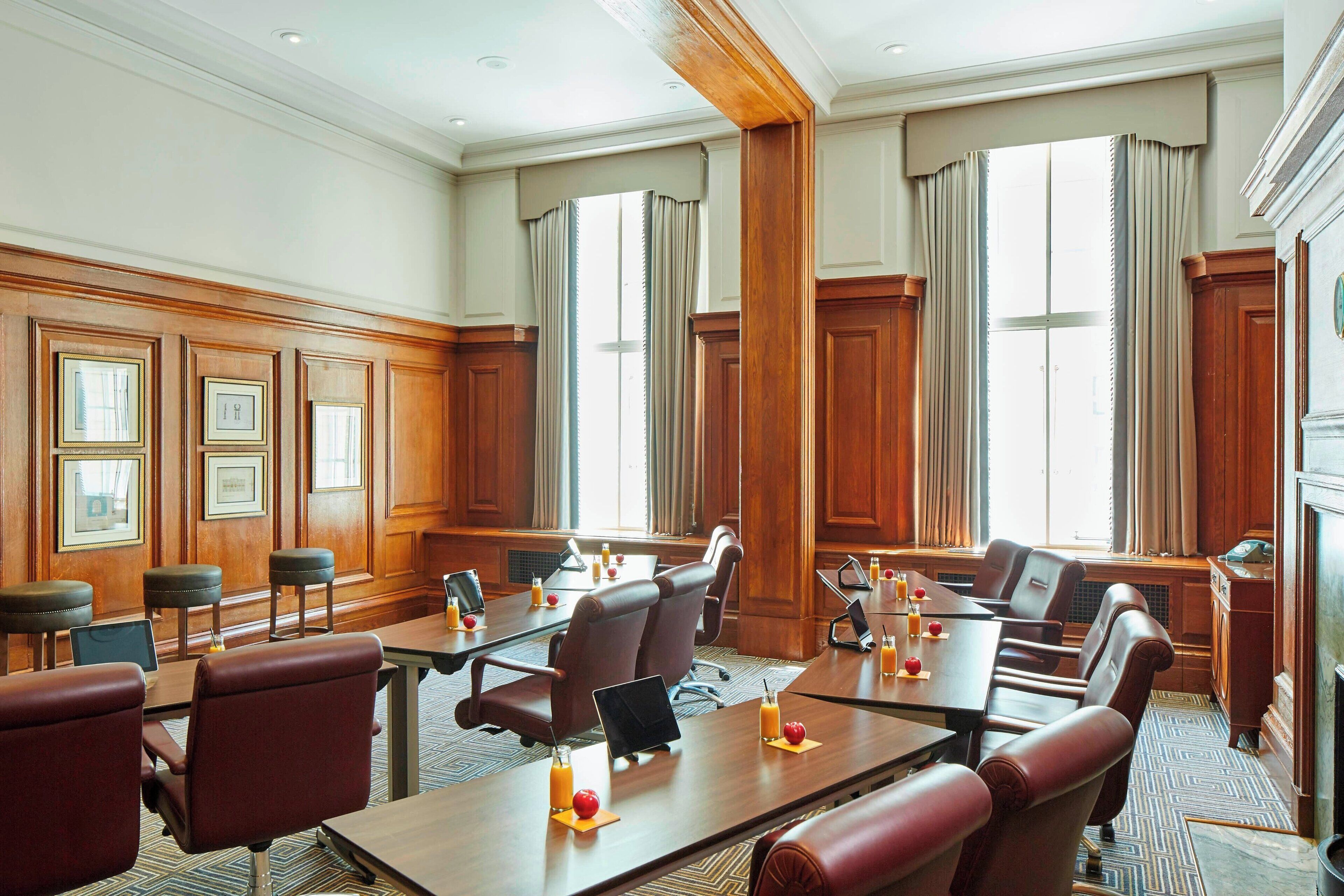 A conference room with wooden paneling, multiple tables, and chairs.