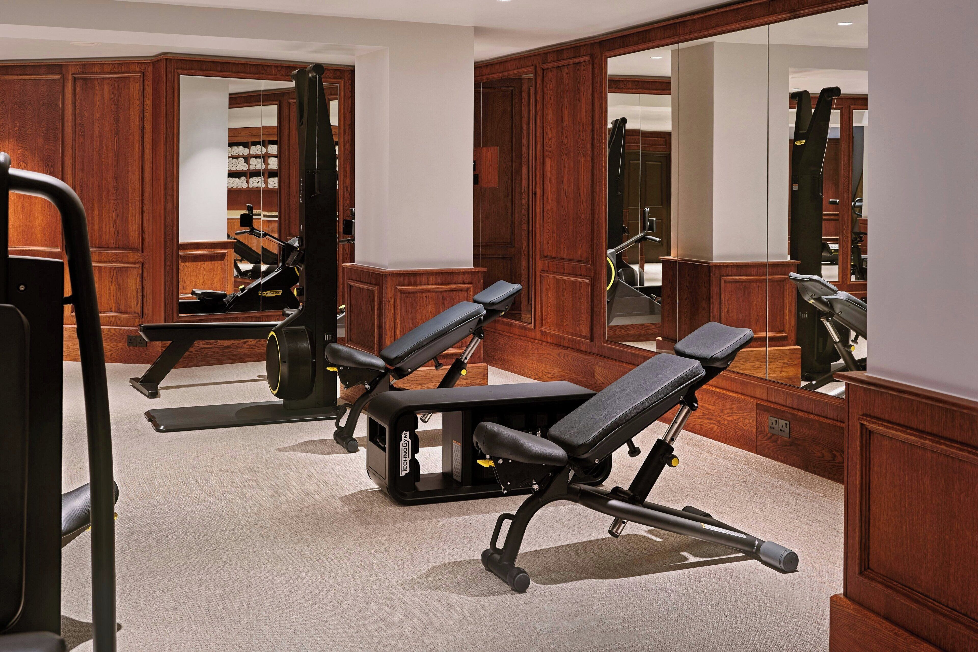 A gym with exercise equipment, wooden cabinets, and a large mirror.