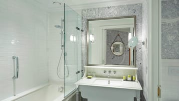 A modern bathroom with a glass-enclosed shower, a white sink with a mirror above it, and a tiled wall with a map design.