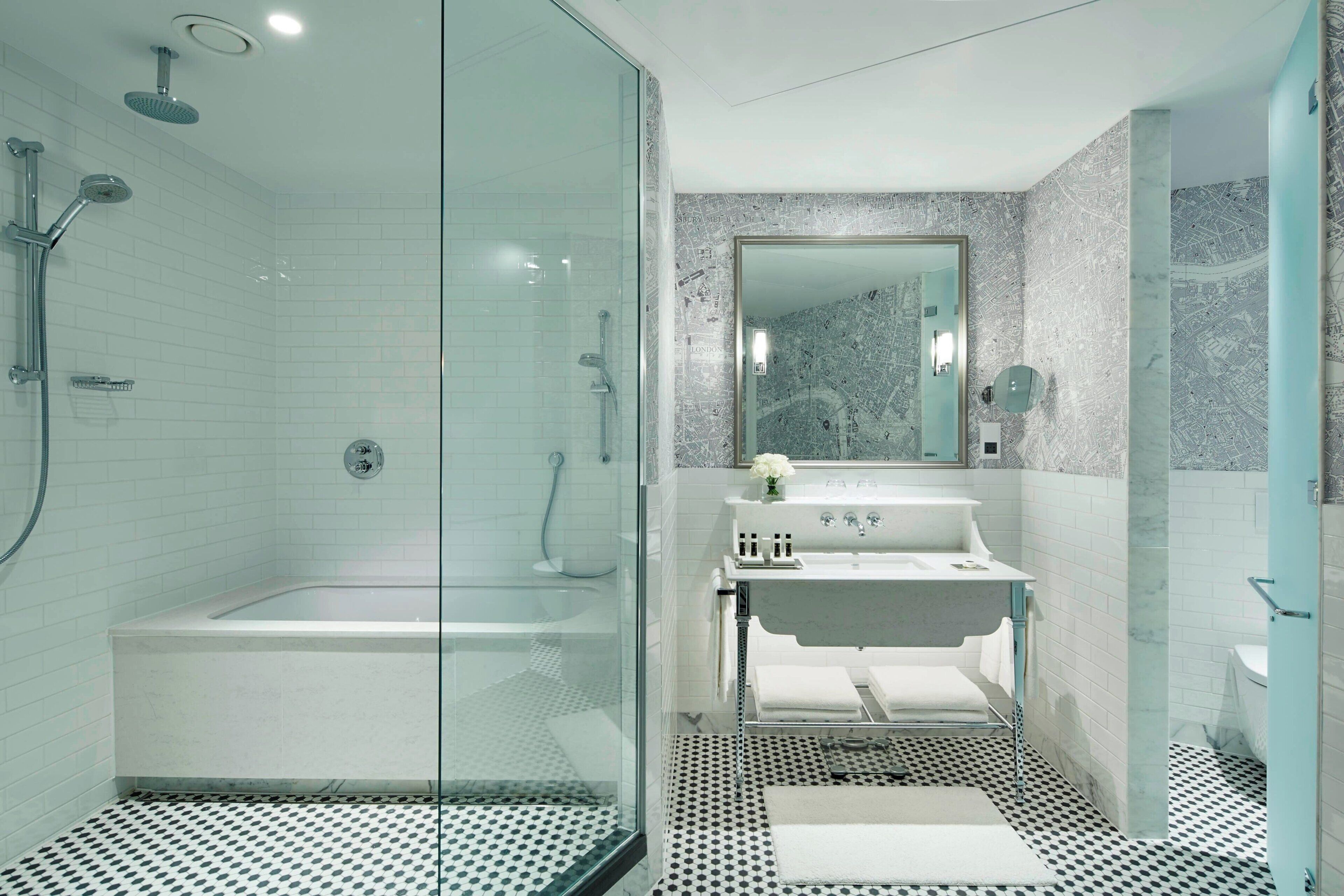 Une salle de bain moderne avec une douche à parois de verre, un lavabo blanc et un mur décoré d’un motif imitant le marbre.