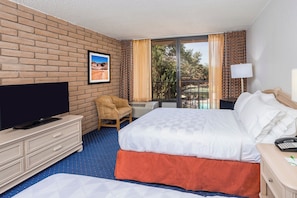 Une chambre d’hôtel avec un mur en briques, une télévision, un lit, une chaise et un balcon avec des rideaux.