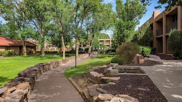 A landscaped pathway with stone borders, a grassy area, and trees.
