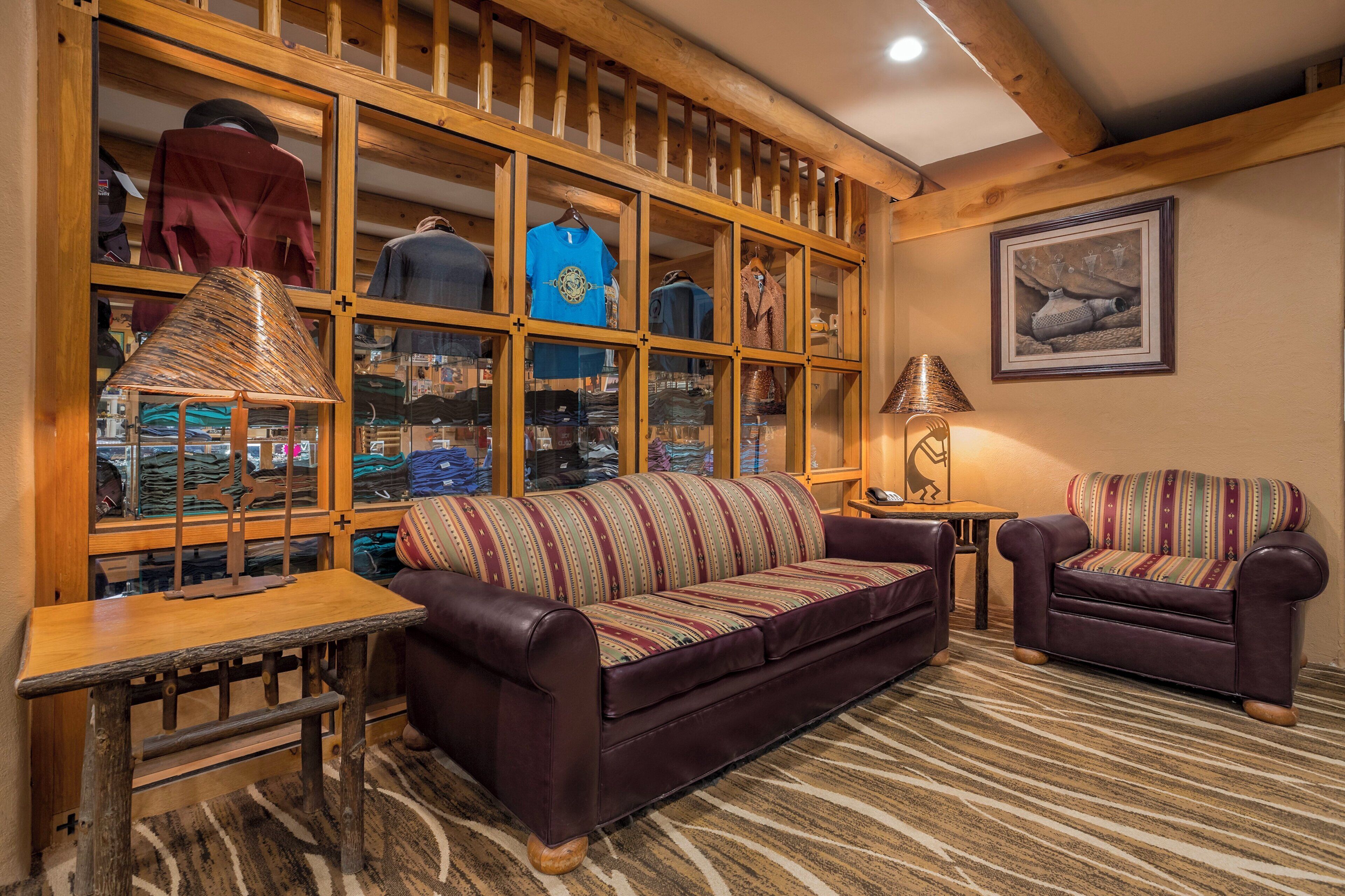 A cozy living room with a leather sofa, a patterned armchair, and a wooden display cabinet filled with various items.