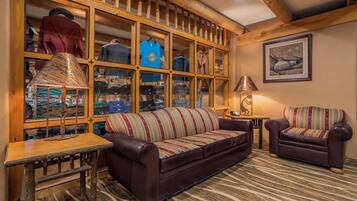 A cozy living room with a leather sofa, a patterned armchair, and a wooden display cabinet filled with various items.