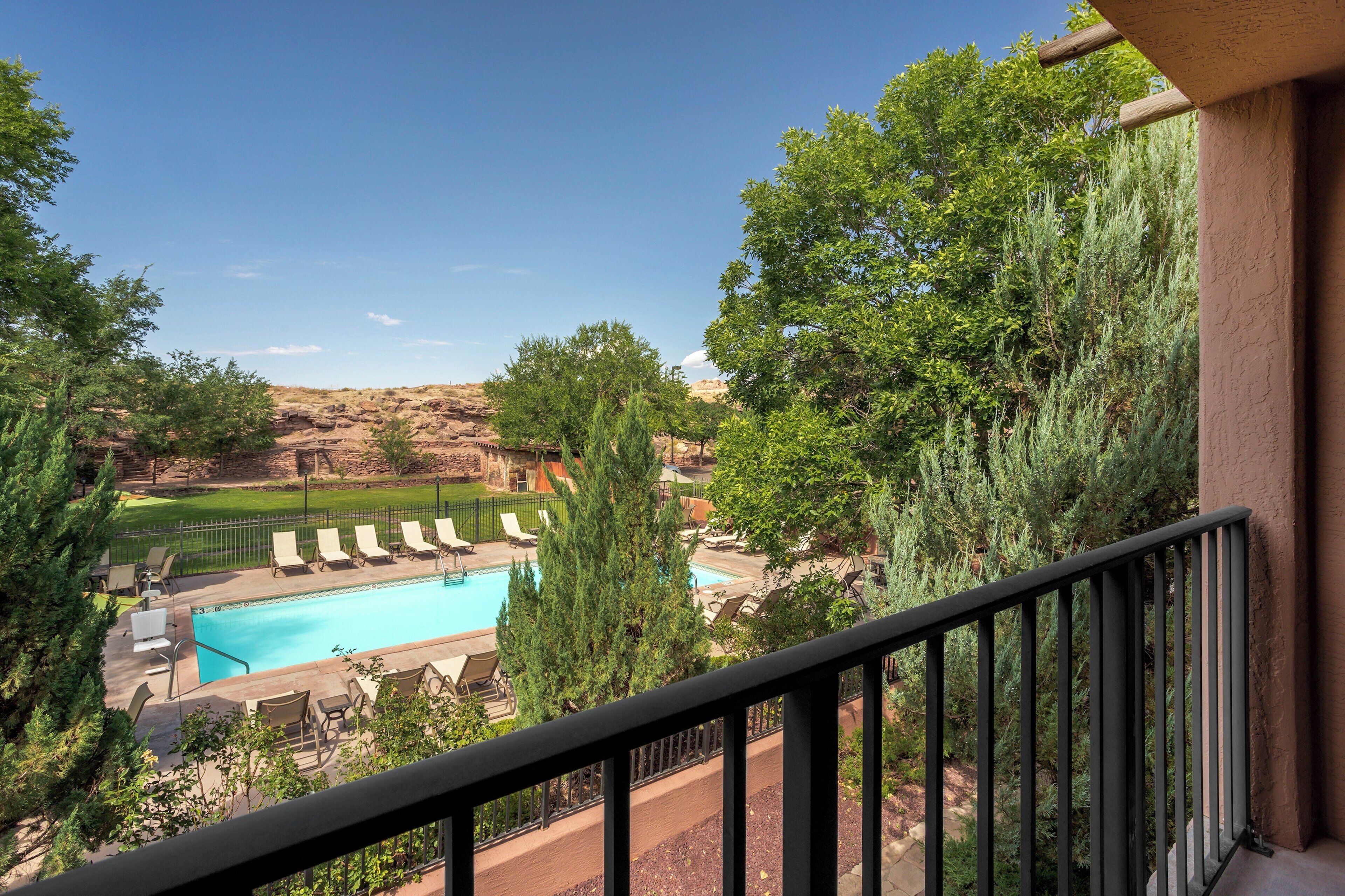 A pool area with lounge chairs and a view of a mountainous landscape.