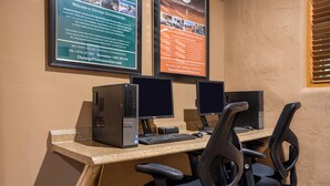 A computer desk with two monitors, a keyboard, and two office chairs.