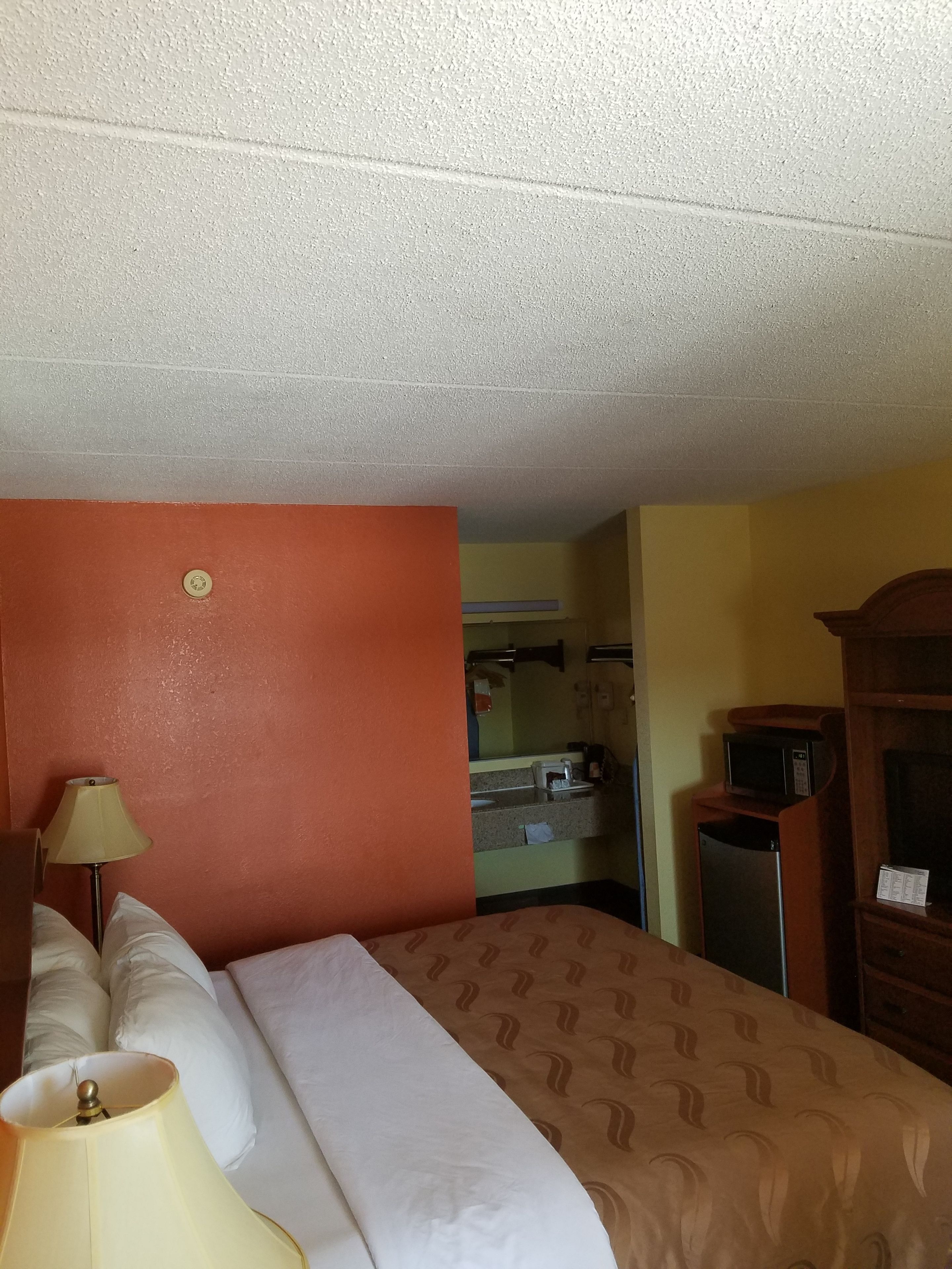 Une chambre d’hôtel équipée d’un lit, d’une lampe, d’un four à micro-ondes et d’un réfrigérateur.