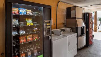 Máquina de vendas com lanches e dispensador de água, máquina de lavar e frigorífico.