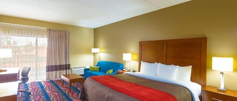 A hotel room with a large bed, a desk, a chair, and a window with curtains.