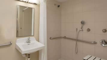 A bathroom with a sink, mirror, shower, and grab bars.