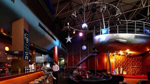 Un bar interior con taburetes, un escenario y una bola de discoteca.