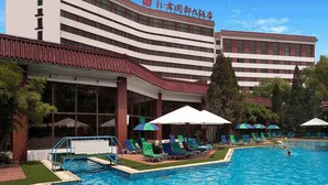 Un hotel con piscina, numerosas tumbonas y sombrillas.