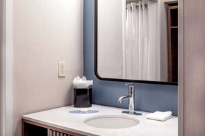 A bathroom with a white sink, a mirror, a towel, and a tissue box.