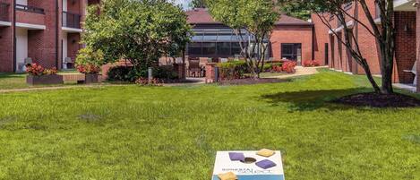 A courtyard with a welcome sign, brick buildings, and green lawns.