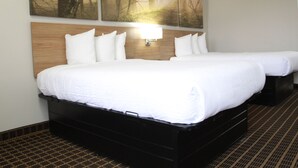 A hotel room with a large bed, a headboard with a light fixture, and a wall-mounted artwork of a forest scene. - Days Inn by Wyndham Forest (Forest)