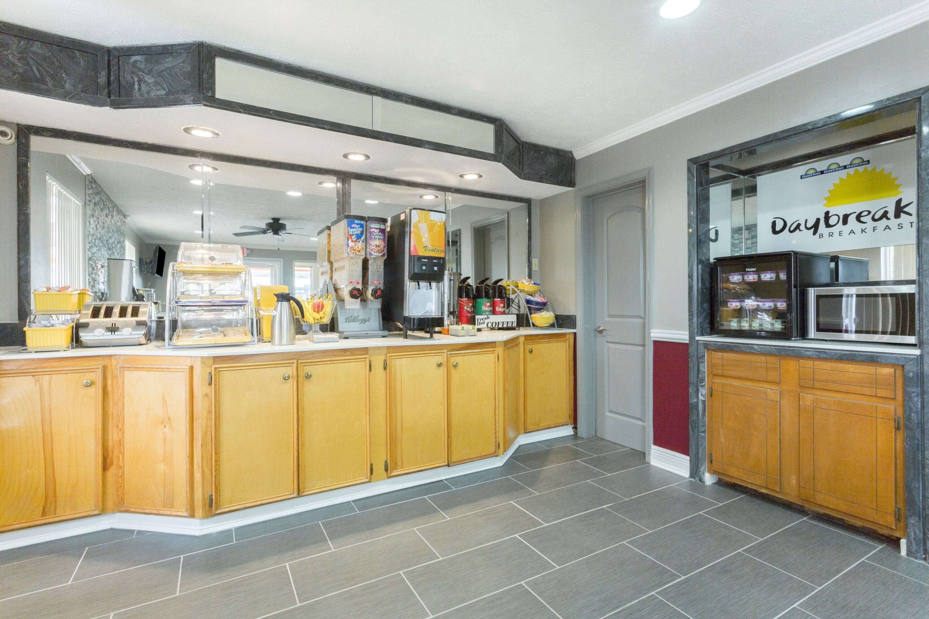 A breakfast area with a counter, coffee machines, and a refrigerator.