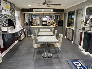 A modern breakfast restaurant with a counter, seating area, and kitchen in the background.