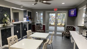 A restaurant with a modern interior, featuring a ceiling fan, a TV mounted on the wall, and a view of the outside through the glass doors. - Days Inn by Wyndham Forest (Forest)