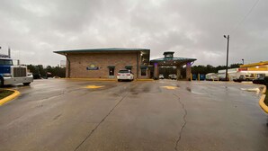 A Days Inn with a brick facade, a covered entrance, and a parking lot with visible cracks. - Days Inn by Wyndham Forest (Forest)