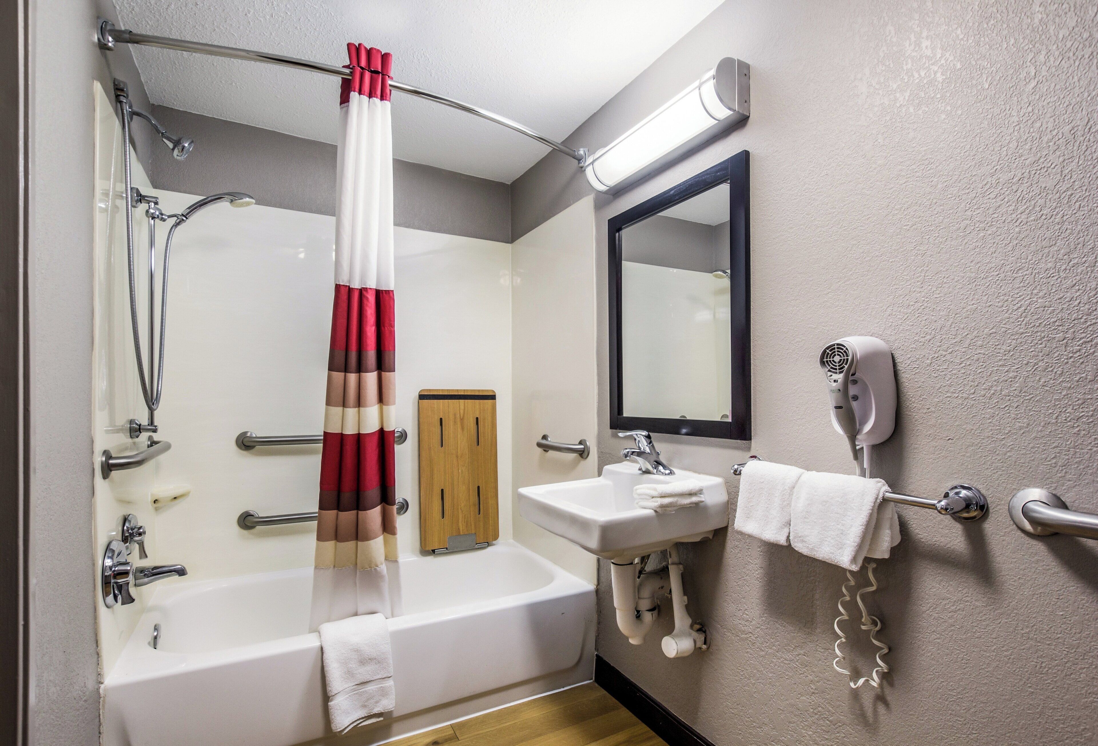 Une salle de bain équipée d’une baignoire, d’une douche, d’un lavabo, d’un porte-serviettes et d’un miroir.