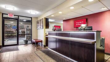 A reception desk with a red wall and a sign indicating free Wi-Fi in all rooms.