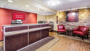 A reception area with a counter, a coffee machine, and a seating area with chairs. - Red Roof Inn Lexington (Lexington)