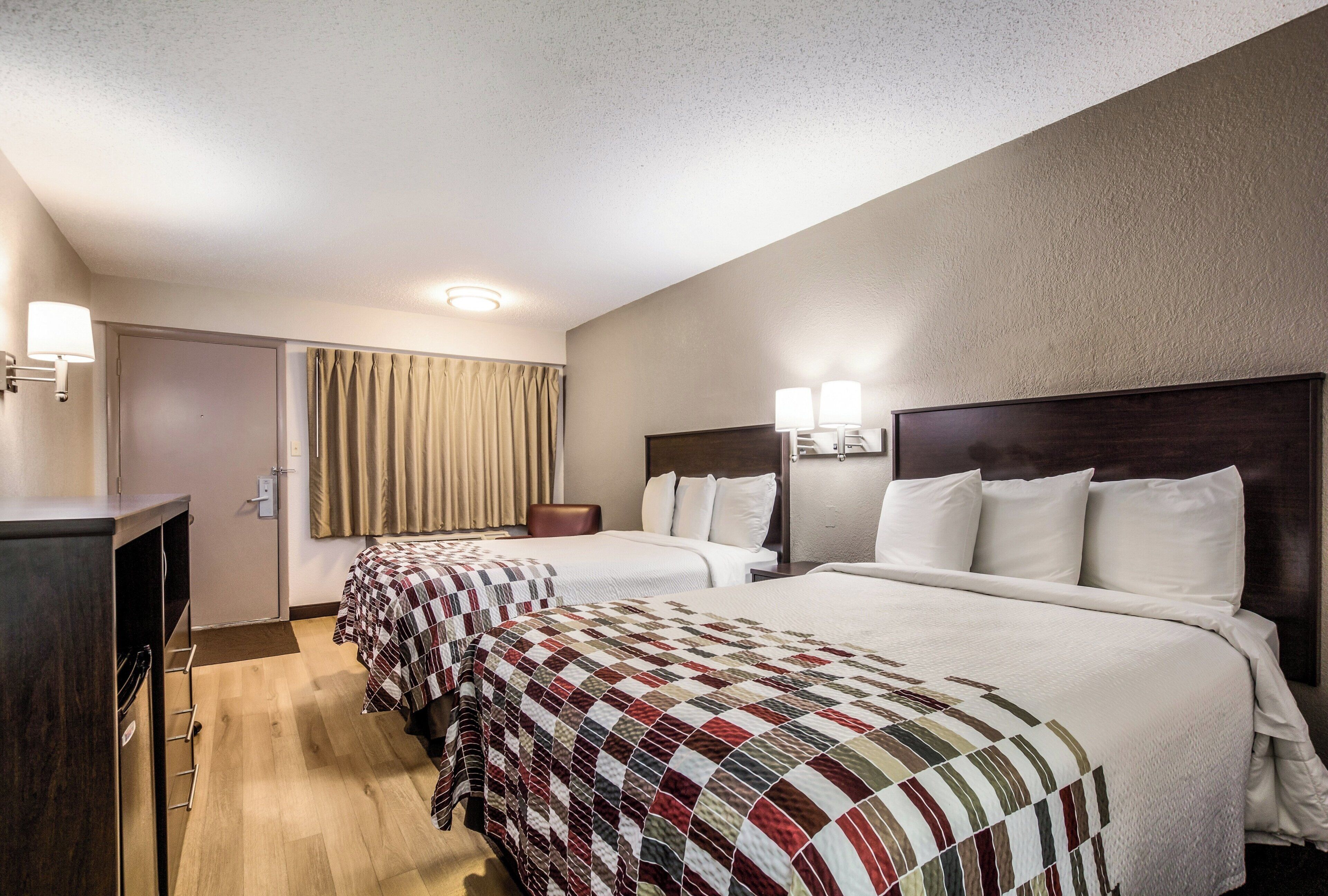 A hotel room with two beds, a desk, and a chair.