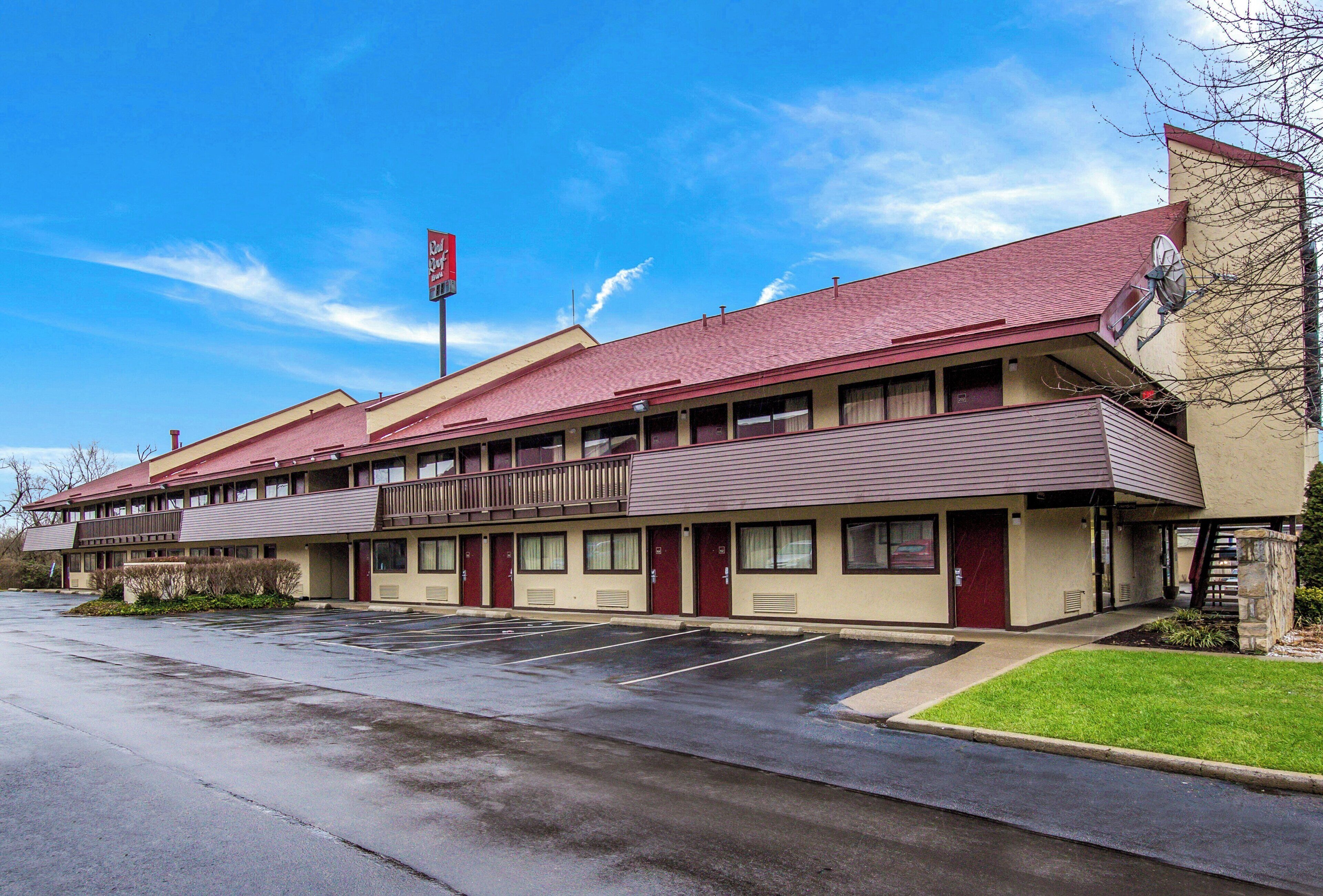 Un motel con una estructura de dos pisos, un estacionamiento y un cielo despejado.