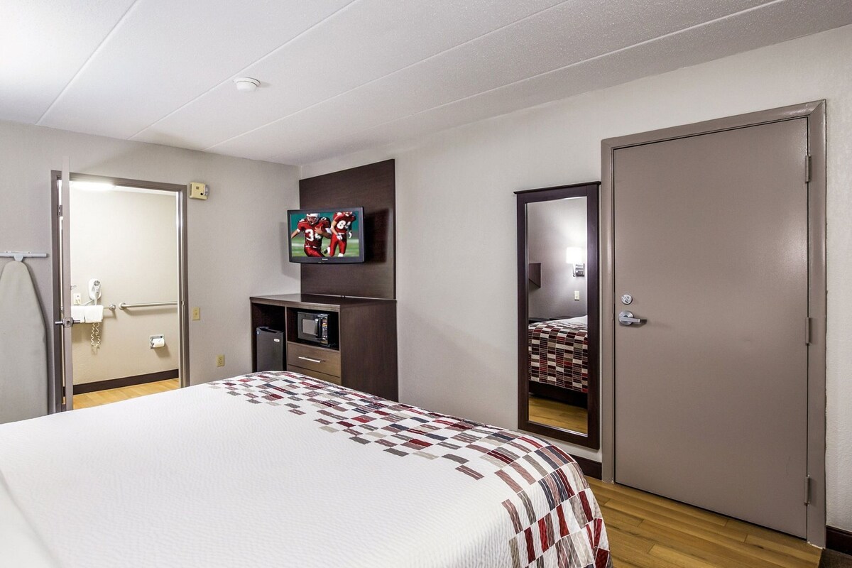 Une chambre d’hôtel équipée d’un lit, d’un téléviseur fixé au mur, d’un four à micro-ondes et d’une armoire.