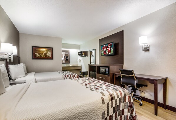 A hotel room with two beds, a desk, a chair, a television, and a bathroom visible in the background. - Red Roof Inn Lexington (Lexington)