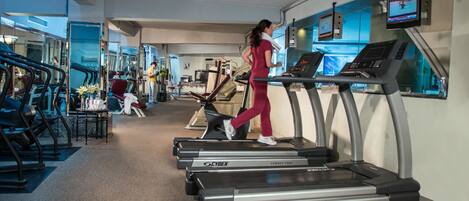Ein Fitnessraum mit Laufbändern, Ergometer und einer Spiegelwand.