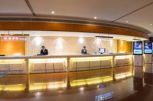 A reception area with a marble counter, receptionists, and digital information kiosks.