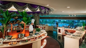A buffet setup with a chef preparing food, surrounded by various dishes and a large window offering a view of the outdoors. - Sunshine Hotel Shenzhen (Shenzhen)