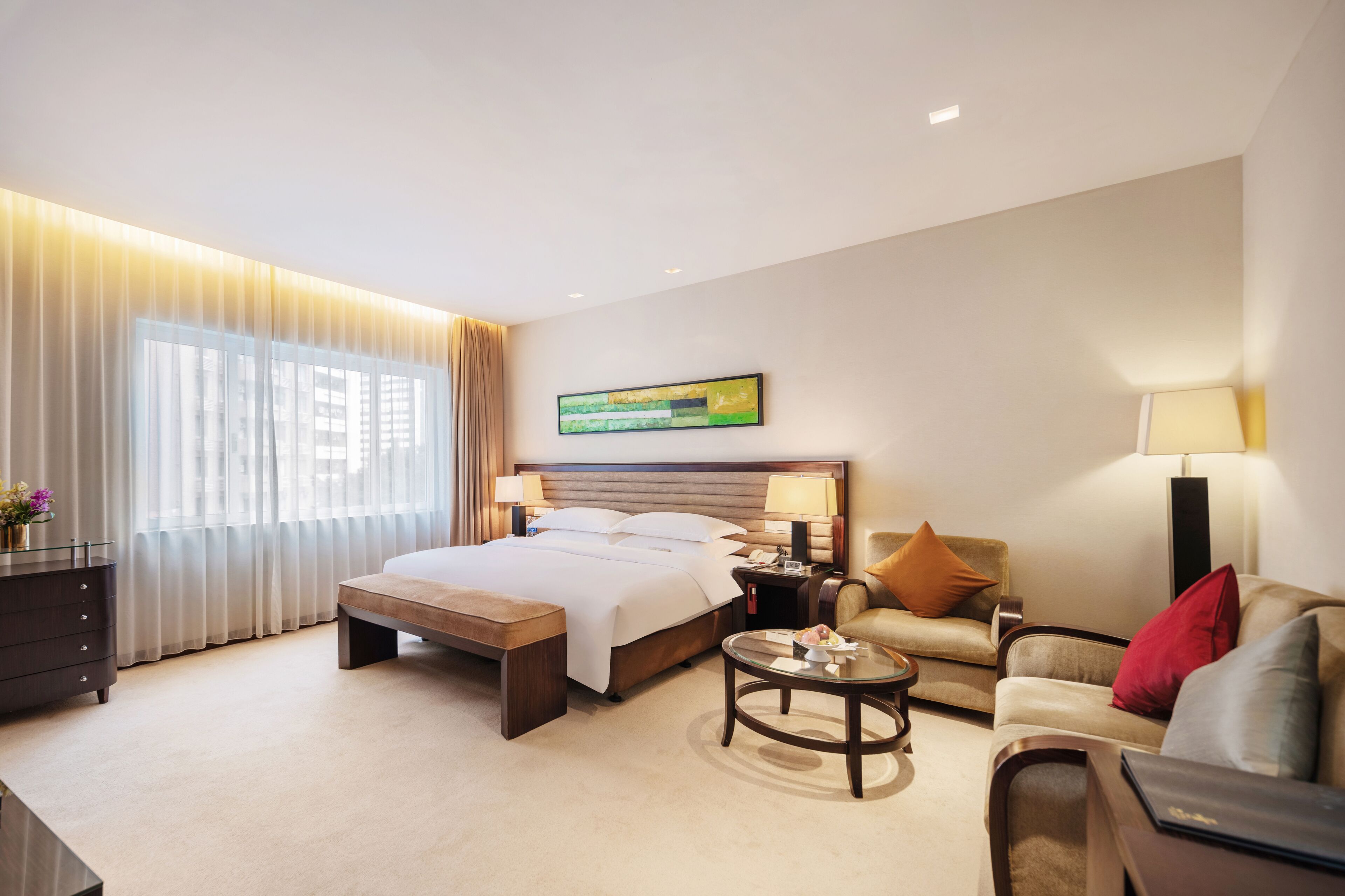 Una habitación de hotel con cama, mesitas de noche, sofá, mesa de centro y escritorio.