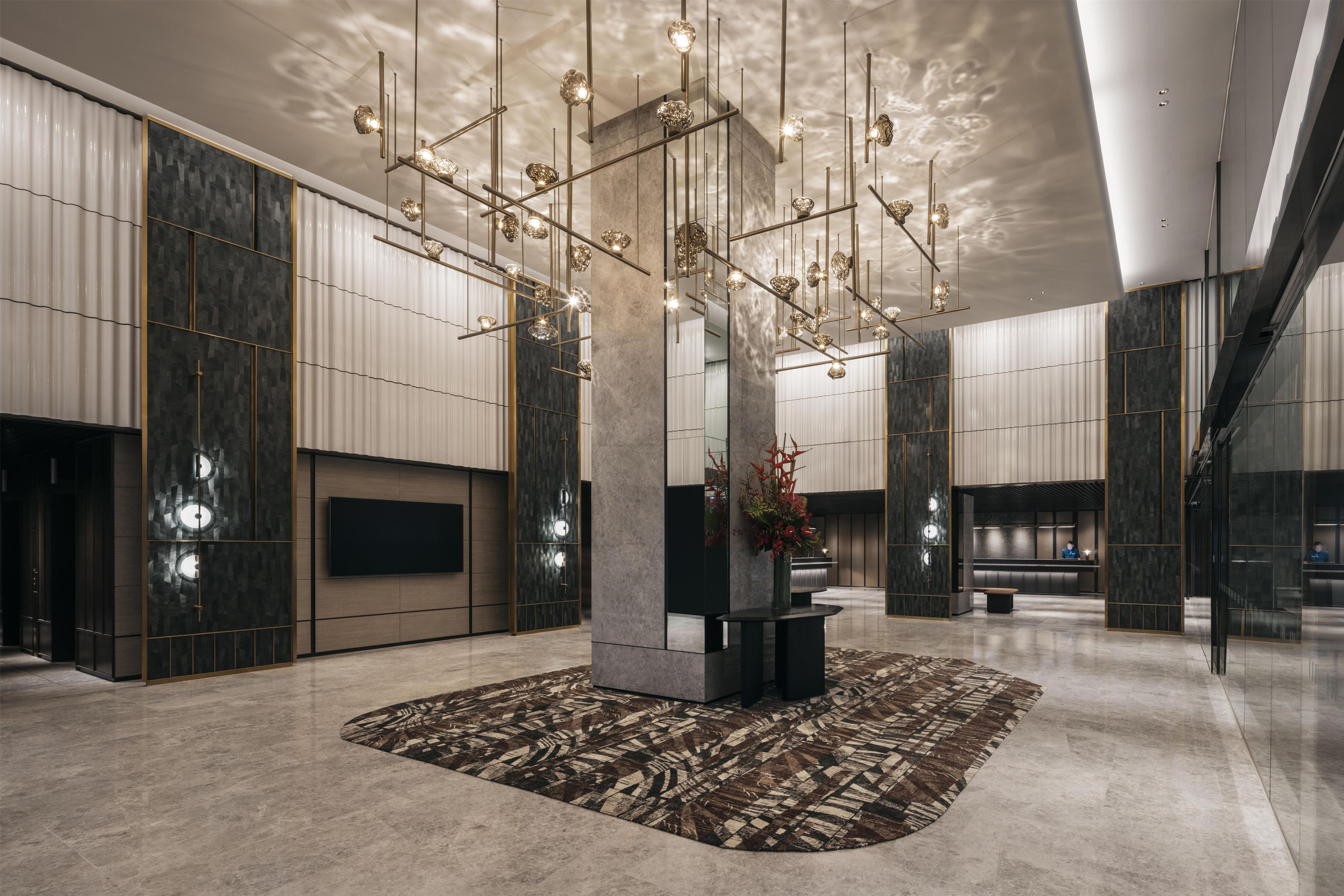 Un hall d’entrée moderne avec une colonne centrale, un téléviseur à écran plat et un comptoir de réception.