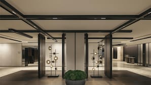Un moderno vestíbulo de hotel con una planta en maceta central, luminarias geométricas y un diseño limpio y minimalista.