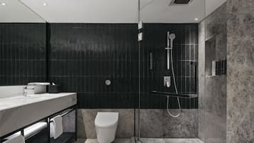 A modern bathroom with a marble sink, a toilet, and a glass-enclosed shower area.