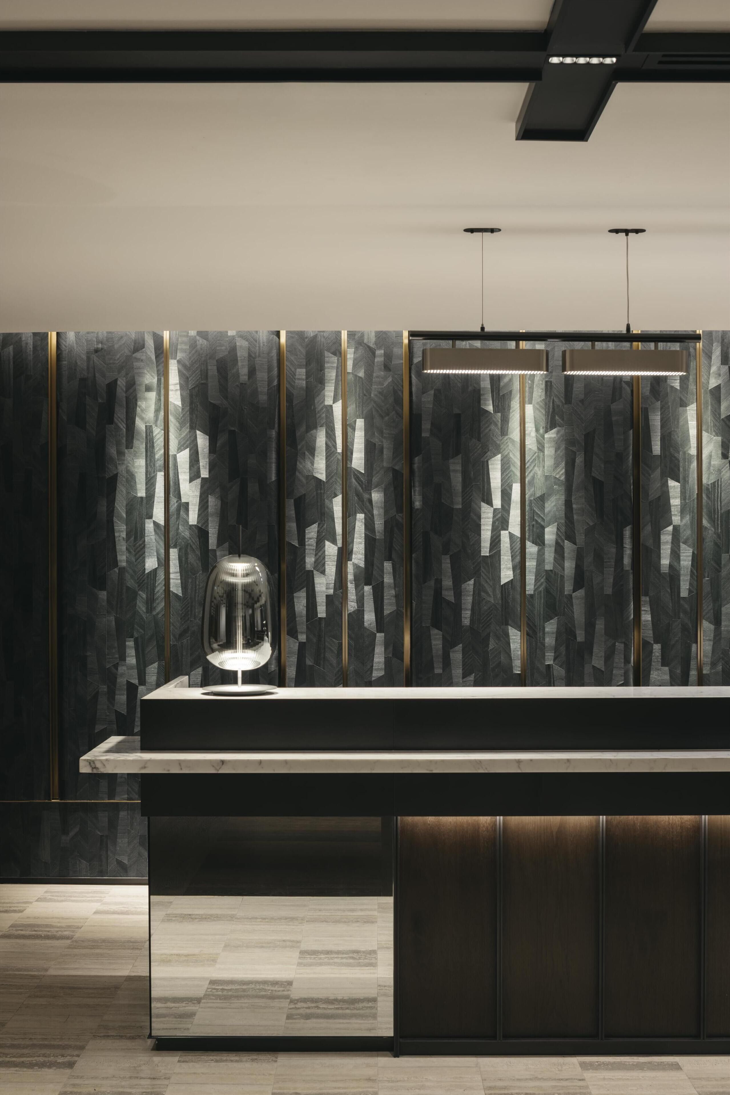 A modern kitchen with a marble countertop, a glass-top coffee station, and a patterned backsplash.