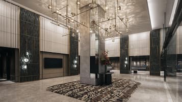 A spacious lobby with a modern chandelier, a central pillar, and a patterned rug.