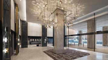 Un vestíbulo amplio con una columna central grande, luminarias modernas y una alfombra estampada.