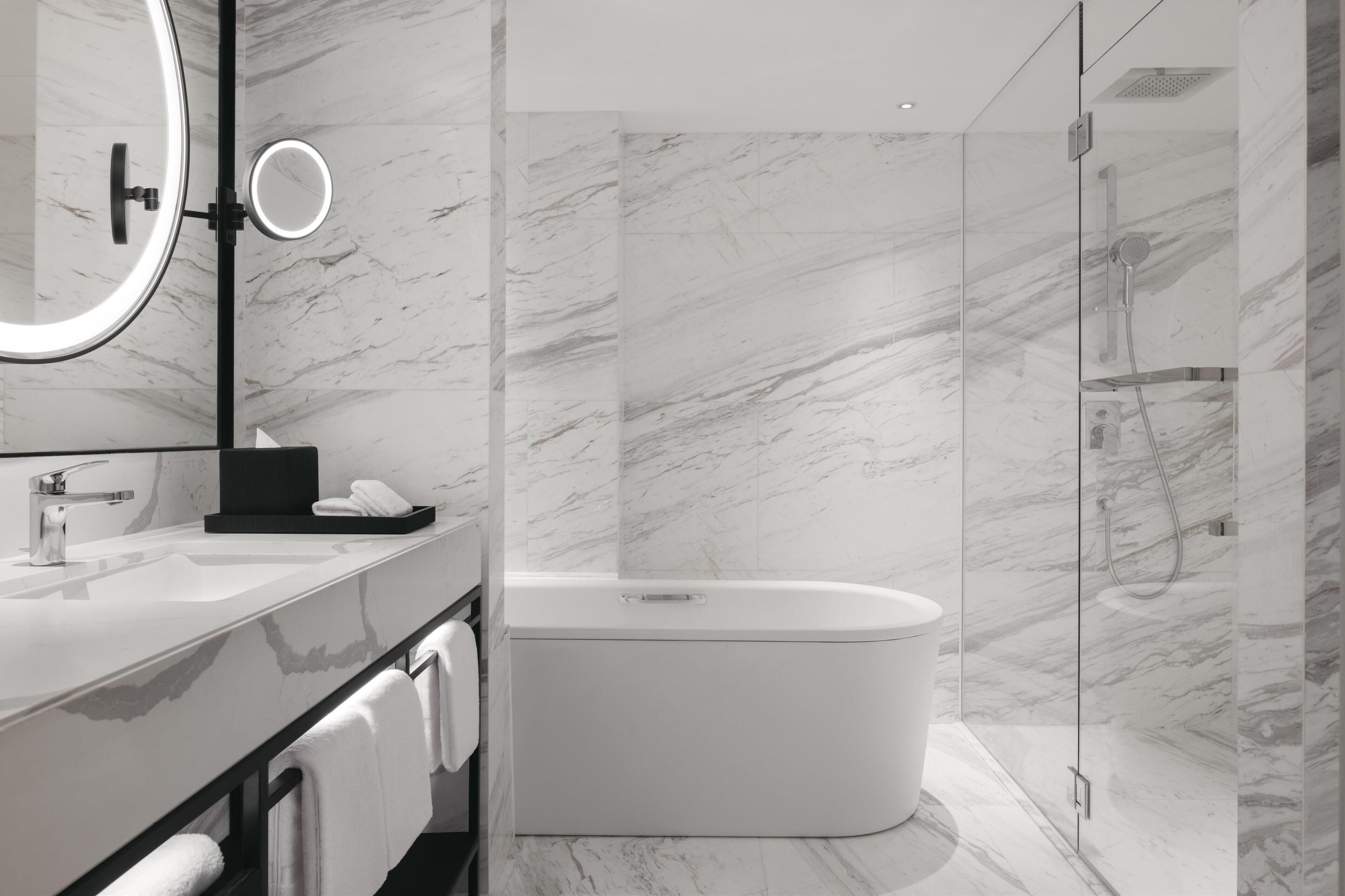 A modern bathroom with a freestanding bathtub, a large mirror, and a glass-enclosed shower area.