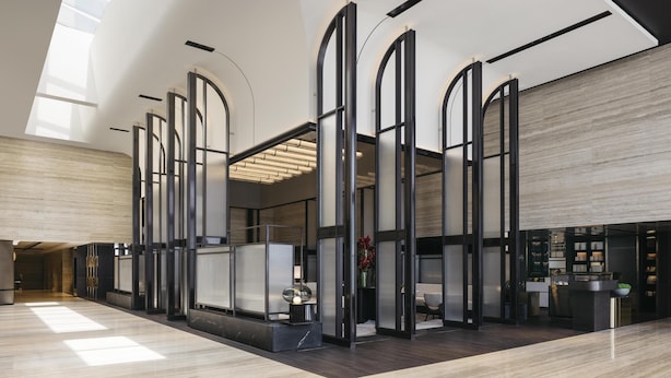 Un moderno vestíbulo de hotel con techos altos, una zona de estar central y un mostrador de recepción.