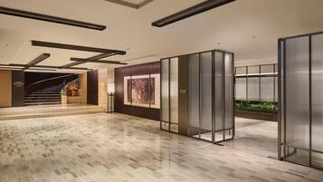 A modern lobby with a polished floor, a staircase, and a meeting room.