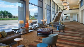 Un hall d’entrée spacieux au design moderne, comprenant un espace détente avec des canapés et des fauteuils, une table basse et un escalier menant aux étages supérieurs.