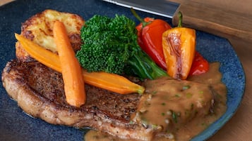 A plate with a steak, carrots, broccoli, and a red bell pepper.